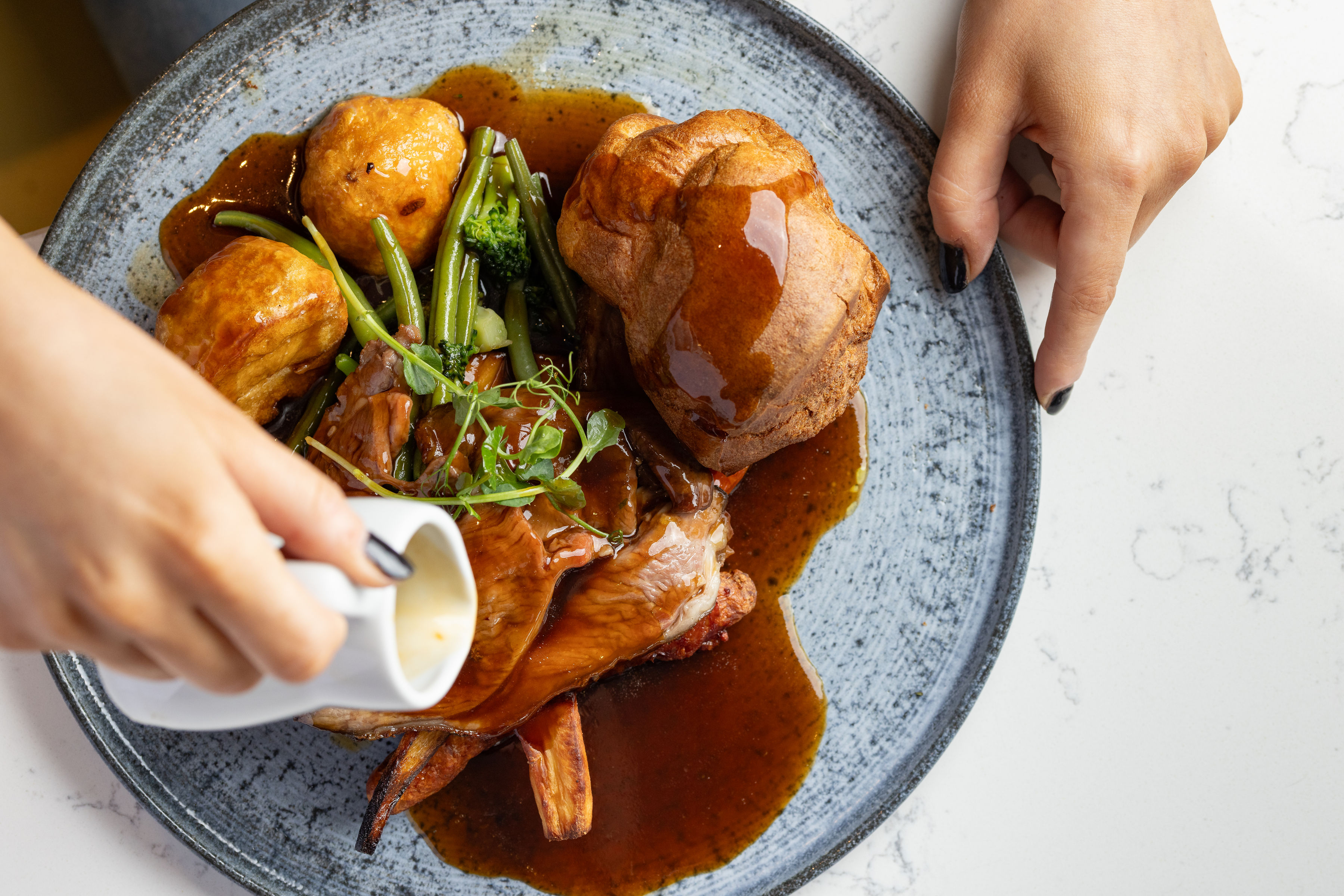 Pouring gravy over a Sunday roast at Banana Wharf